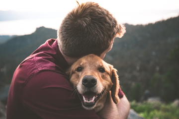 man hugging his dog on their hike
